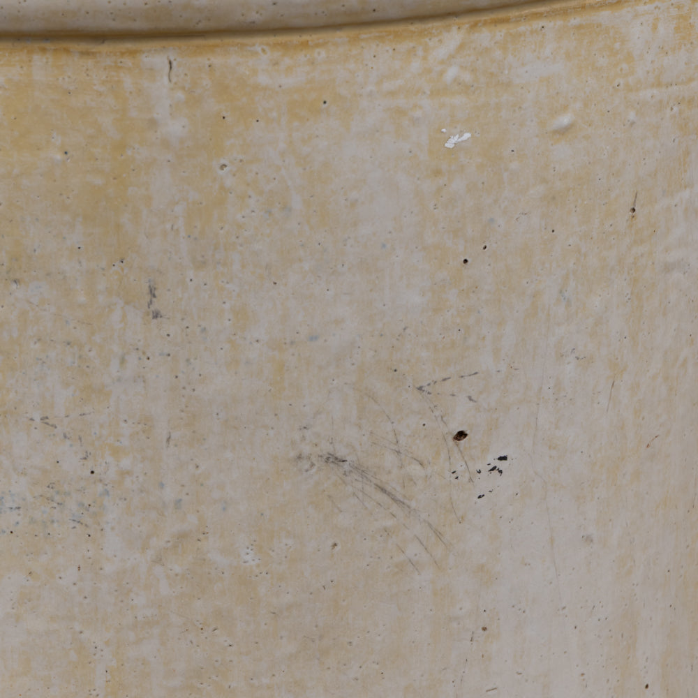 A close-up of a textured, warm beige ceramic surface with subtle speckles and minor scuffs.