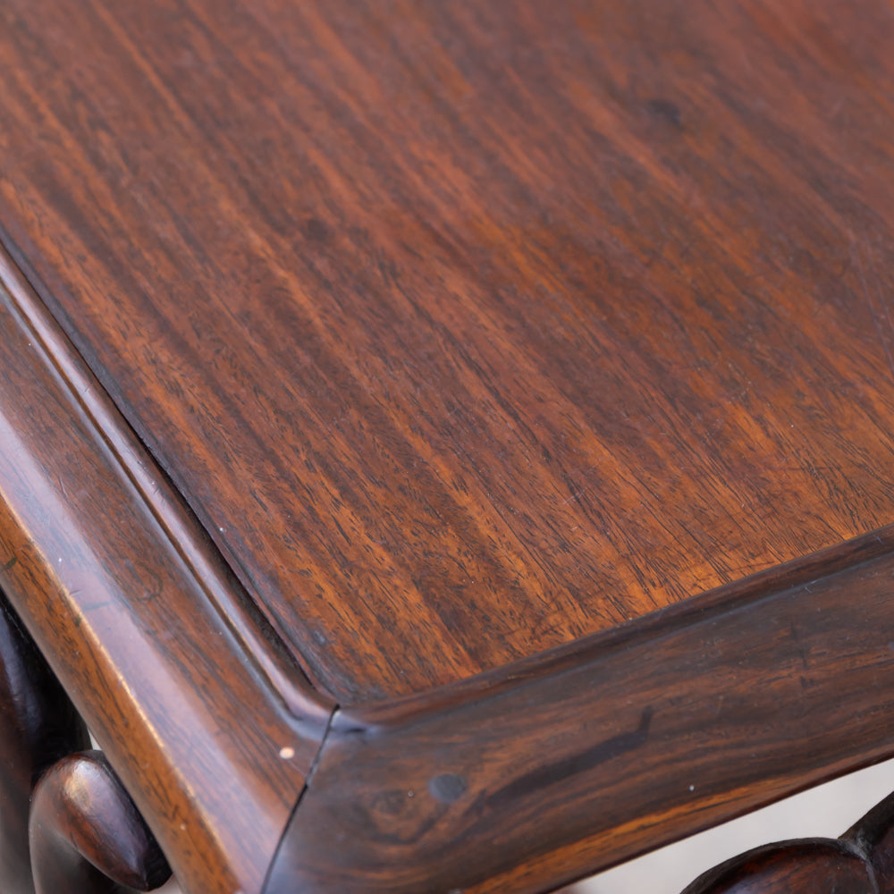 Close-up of a dark brown wooden table corner showing the rich wood grain and polished finish.