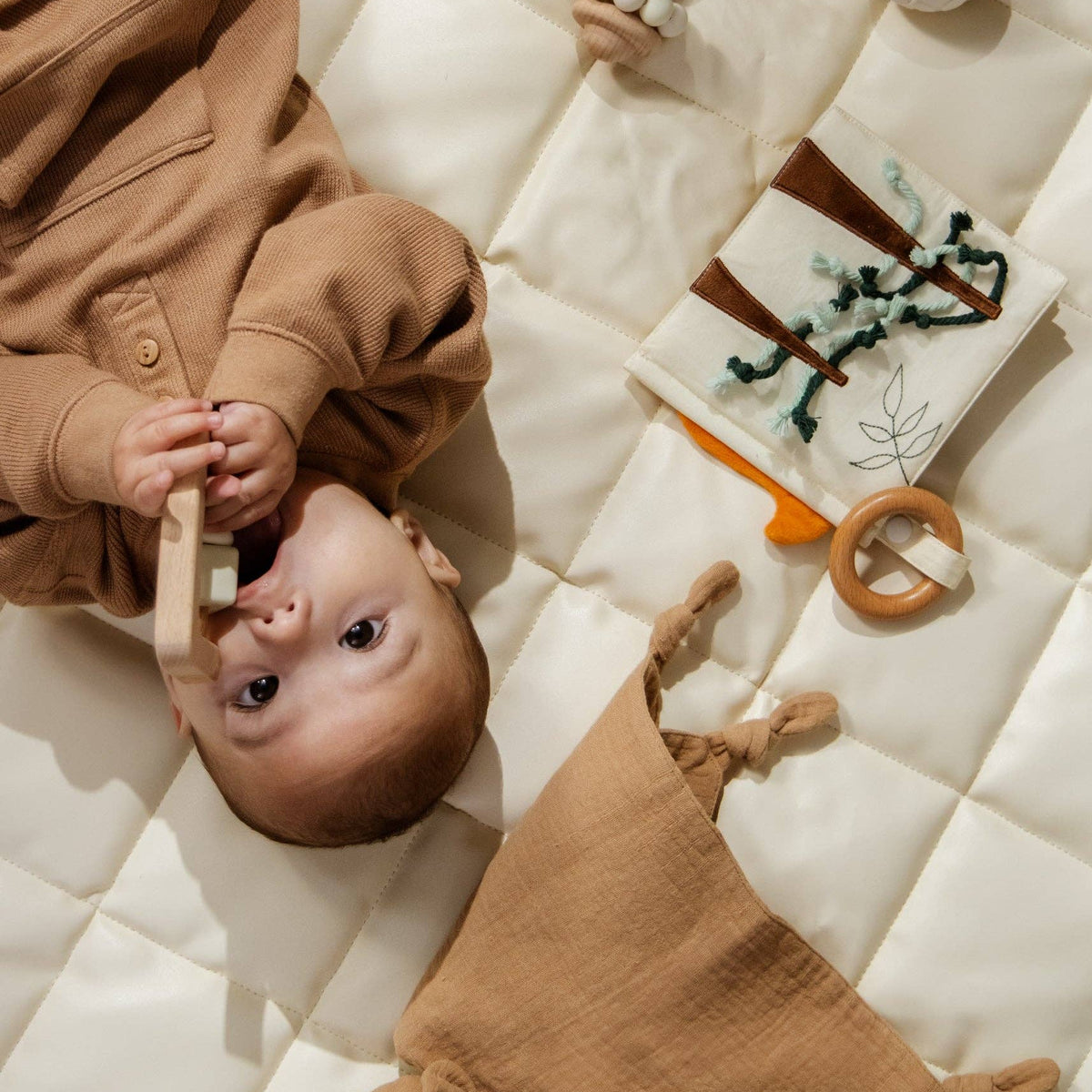 Baby lying on a quilted surface with toys around