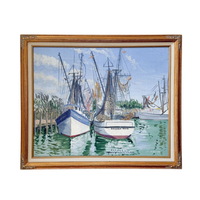 A framed watercolor painting of harbor boats on the water, enclosed in a decorative gold-toned wooden frame. The painting depicts several fishing boats moored in green water under a blue sky with white clouds.