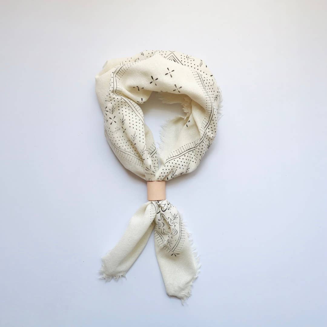 Cream-colored scarf with intricate patterns on a light gray background