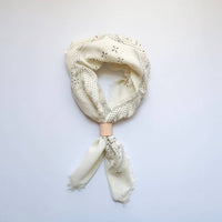 Cream-colored scarf with intricate patterns on a light gray background