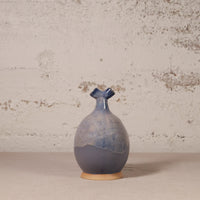 Blue ceramic vase on a beige surface with a textured wall background