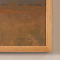 Close-up of a framed painting showing textured earthy brown and orange brushstrokes, with a light natural wood frame against a neutral wall.