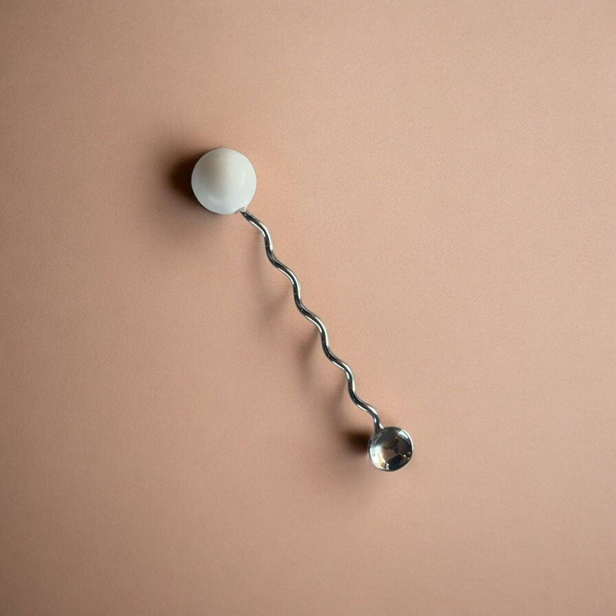 Wall-mounted lamp with a curved arm and spherical ends on a beige background