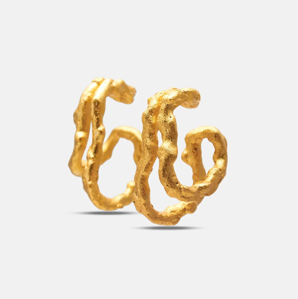 A pair of textured gold huggie hoop earrings with an organic, wavy, tree-bark-like surface, displayed on a clean light gray background.