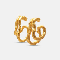 A pair of textured gold huggie hoop earrings with an organic, wavy, tree-bark-like surface, displayed on a clean light gray background.