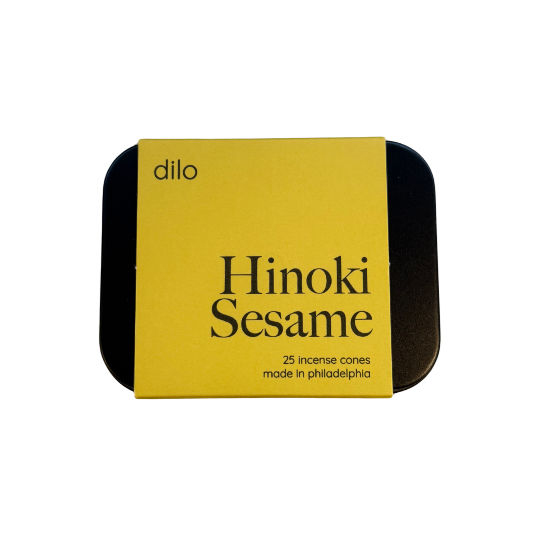 A square tin of Dilo Hinoki Sesame incense cones, featuring a bright yellow label with black text and a black metal tin visible on the sides, set against a plain white background.