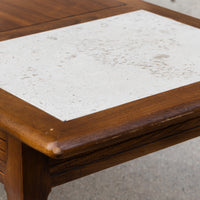 A close-up of a wooden table with a distressed white stone tile inlay on the tabletop.