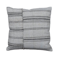 A square throw pillow made from a light beige woven textile with horizontal dark gray stripes, displayed on a rustic gray wooden plank surface.