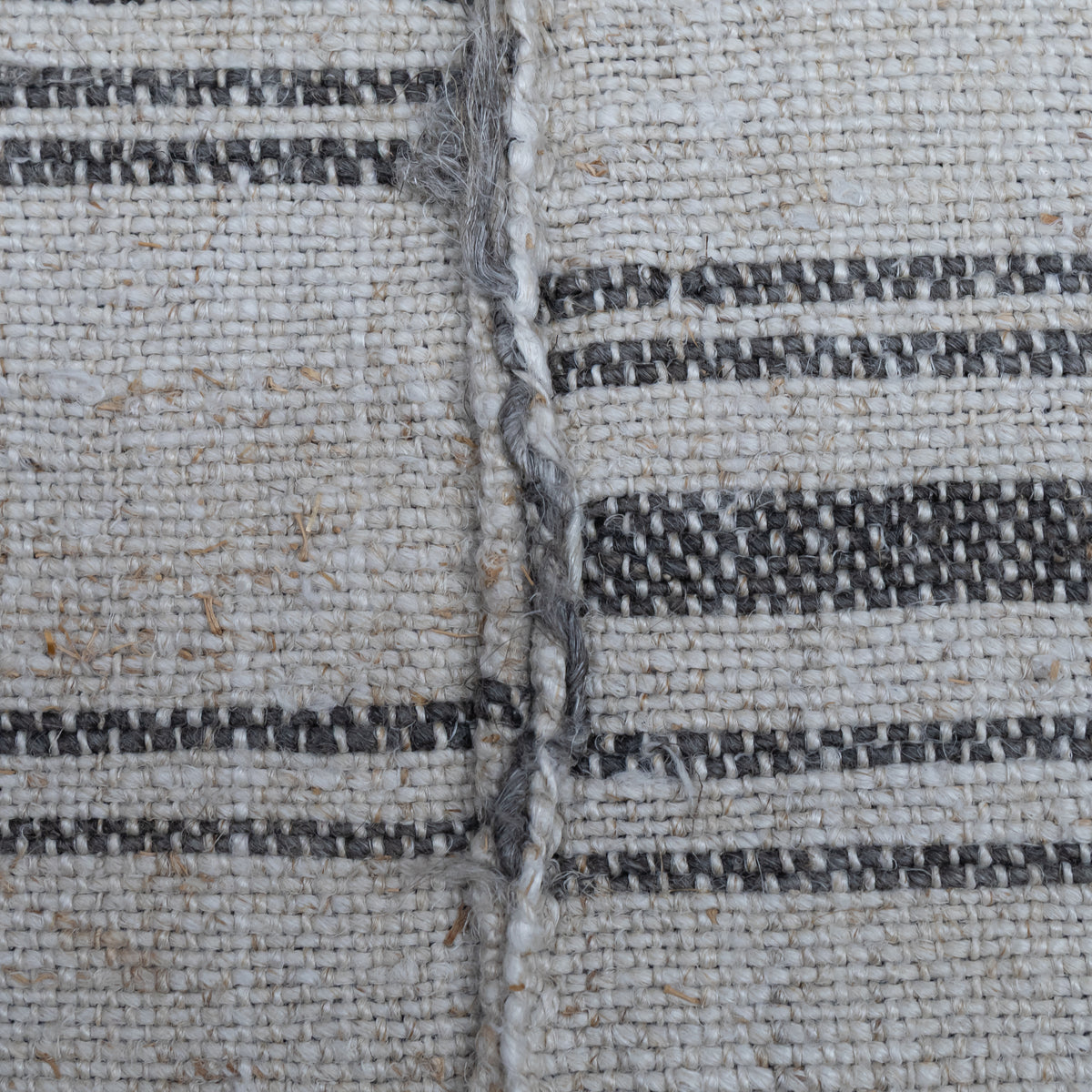 Close-up of a woven textile surface with a natural off-white base and dark charcoal gray horizontal stripes, showing the texture and weave detail.