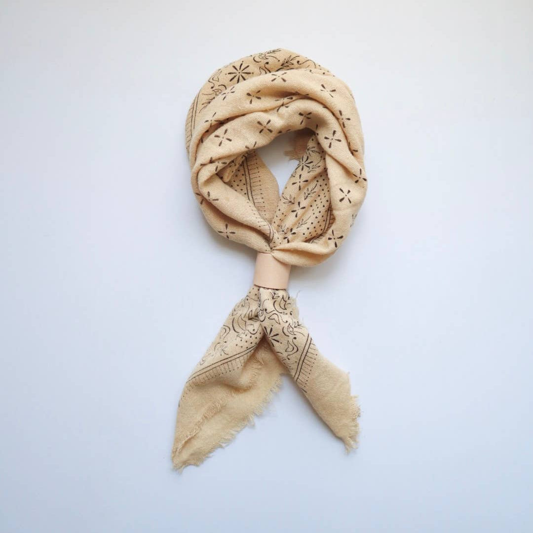 Beige scarf with intricate patterns on a light gray background