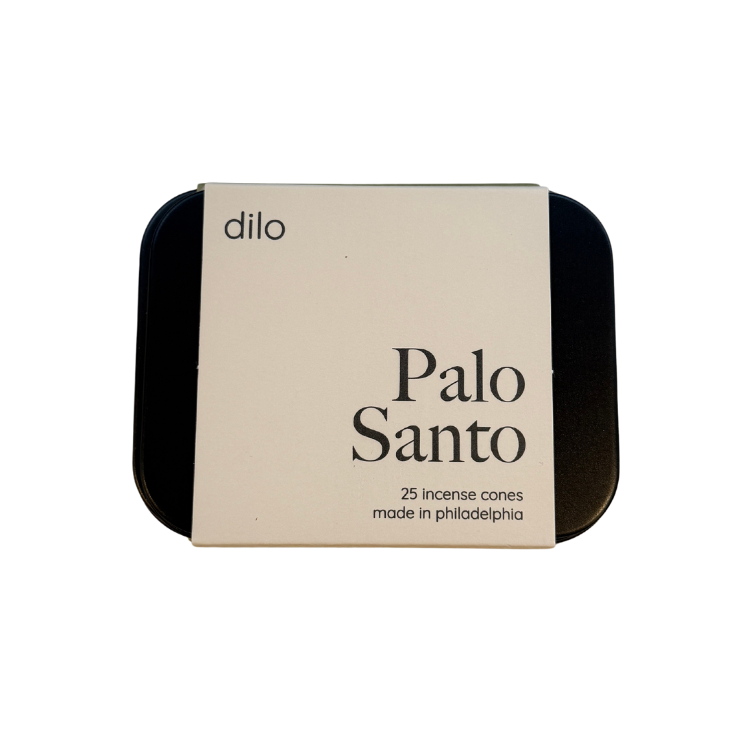 A square metal tin of Dilo Palo Santo incense cones, featuring a cream-colored paper label with black text, set against a plain white background.