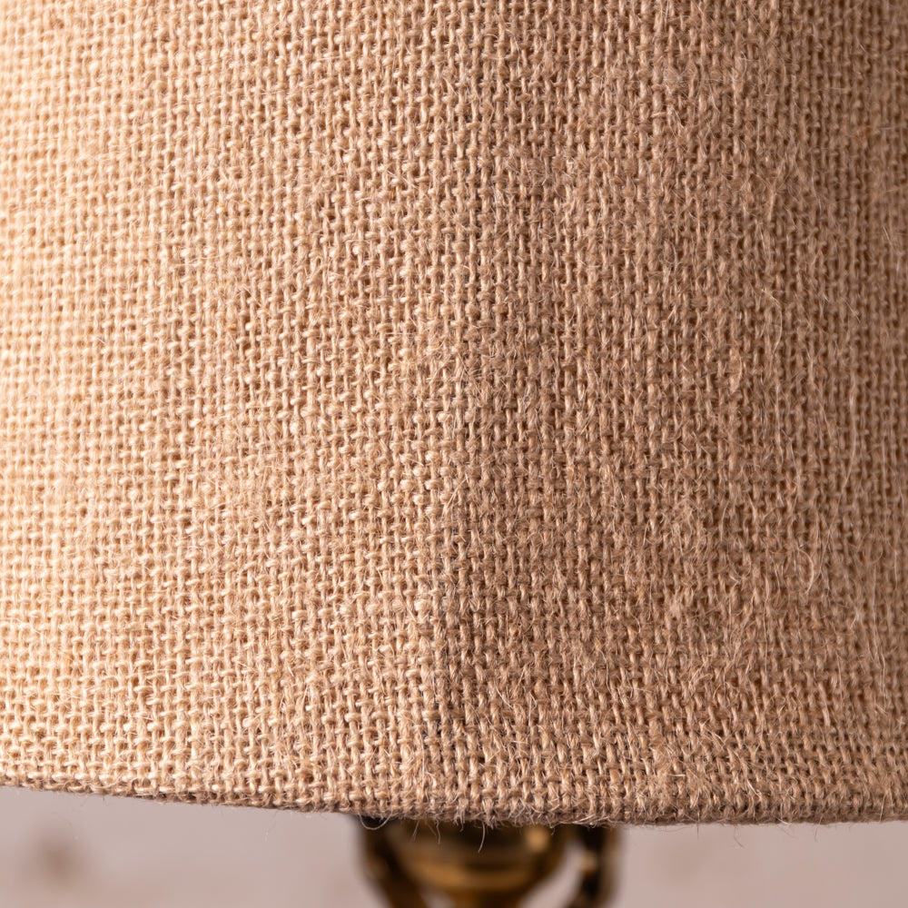 Close-up of a natural burlap lampshade showing its coarse woven texture in a warm tan color.