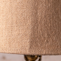 Close-up of a natural burlap lampshade showing its coarse woven texture in a warm tan color.