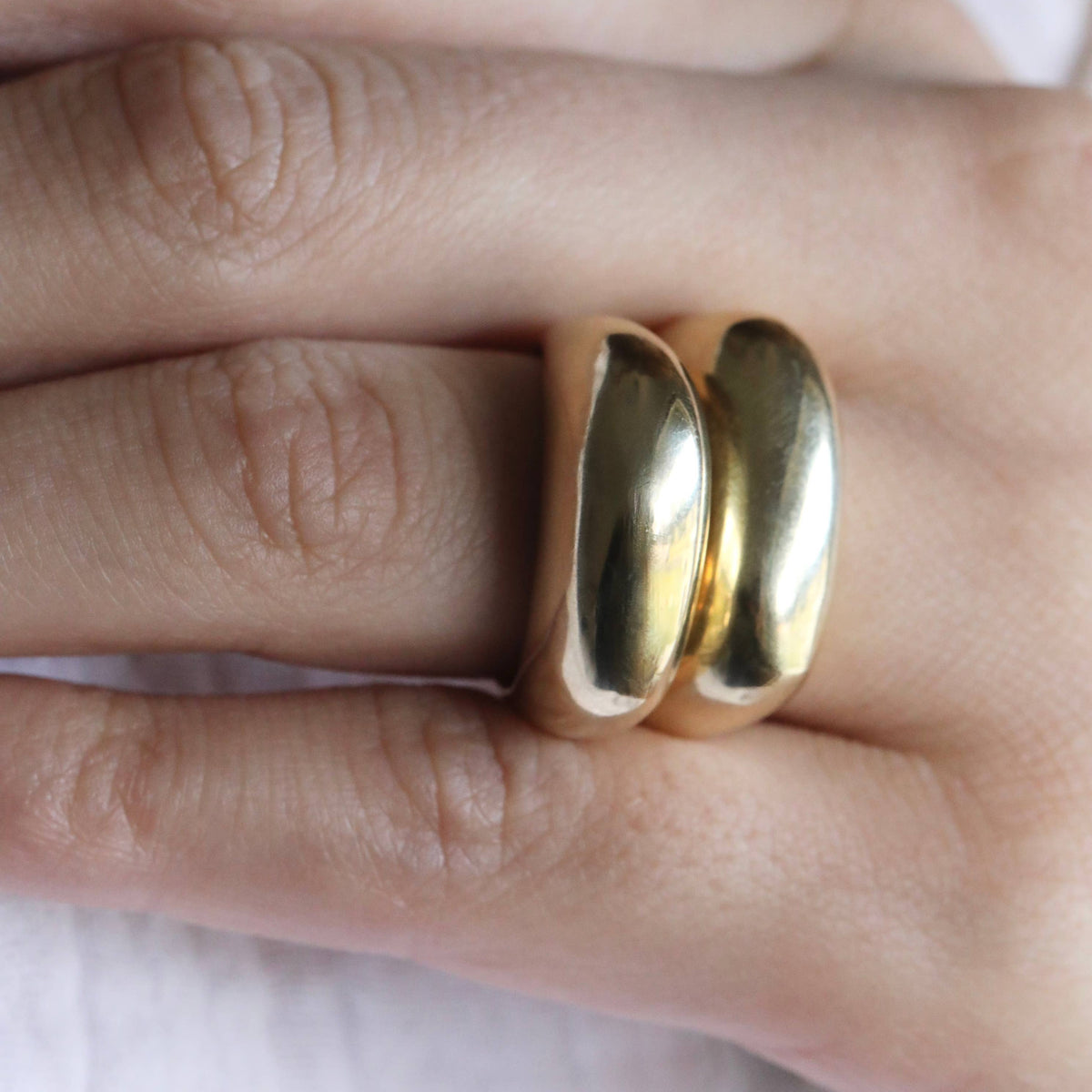 Gold ring on a person's finger against a white background