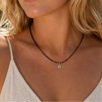 Woman wearing a necklace with a small pendant outdoors