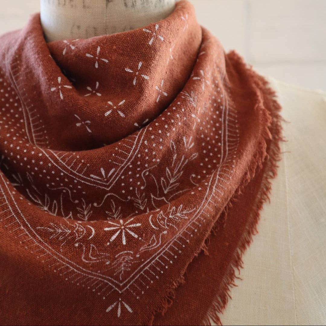 Brown patterned scarf wrapped around a cylindrical object with text on a white background