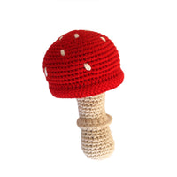 Crocheted mushroom toy with red cap and beige stem on a white background