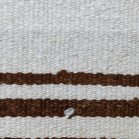 Close-up of a woven textile with a warm off-white background and two horizontal medium-brown stripes.
