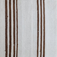 A close-up of a woven textile with a cream-colored background and vertical dark brown stripes.