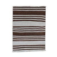 A rectangular woven textile with vertical stripes in dark brown, light gray, and white, featuring fringed edges, shown against a plain off-white background.