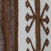 Close-up of a woven textile showing a vertical striped pattern in dark brown and medium brown on the left, and a cream background with a brown geometric diamond motif on the right.