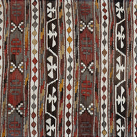 A close-up of a woven textile with vertical tribal-style stripes in red, brown, black, white, gray, and muted yellow, showing detailed fabric texture and pattern.