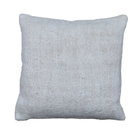 A square throw pillow in a textured, woven off-white fabric, displayed flat on a rustic gray wooden plank floor.
