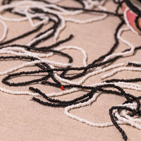 Close-up of loose black and white seed beads arranged on a beige fabric background, with a small red accent bead visible.