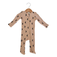 A baby long-sleeve footed sleeper in beige with a black moon phase pattern, hanging on a wooden hanger against a white background.