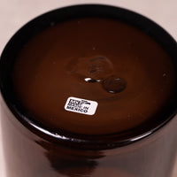 Close-up of the bottom of a dark brown glass vessel, showing a small white label that reads 'MADE IN MEXICO' and the MXF logo.