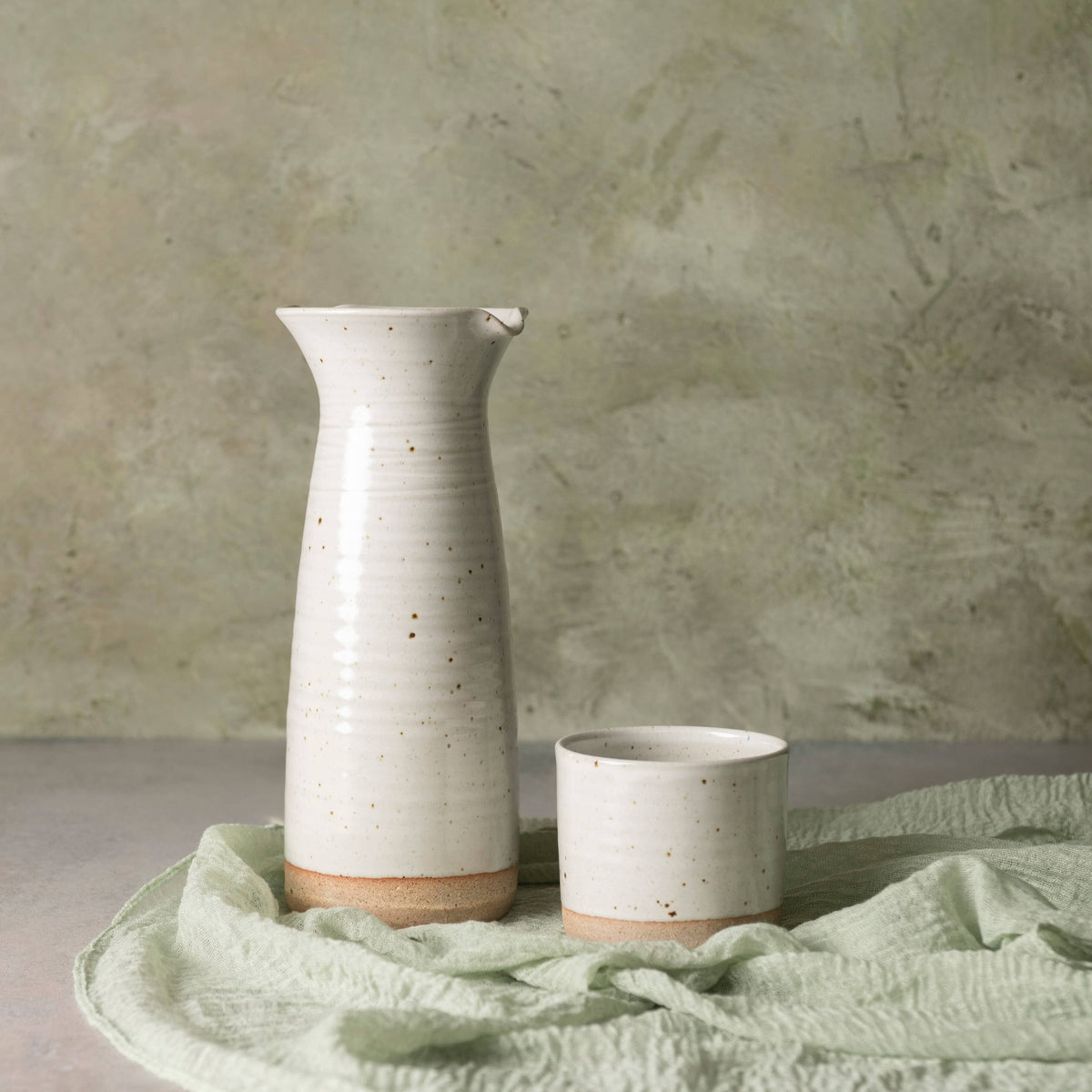 Two ceramic vases on a textured surface with a neutral background