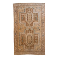 A rectangular vintage-style area rug with a traditional geometric medallion pattern in warm tan, beige, and brown tones with muted blue accents, shown flat against a plain white background.