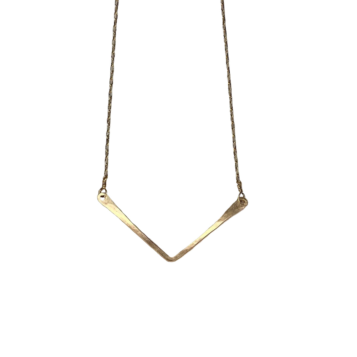 Gold necklace with a V-shaped pendant on a textured stone surface