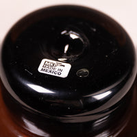 Close-up of the glossy black lid of a dark amber glass bottle, featuring a white 'MADE IN MEXICO' label.