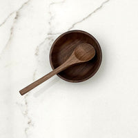 Wooden bowl and spoon on a marble surface