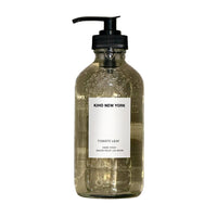 Glass bottle with pump and 'Kiko New York' label on a textured gray background