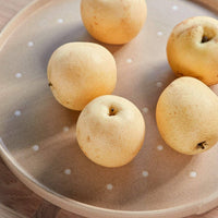 Five apples on a ceramic plate with a polka dot pattern
