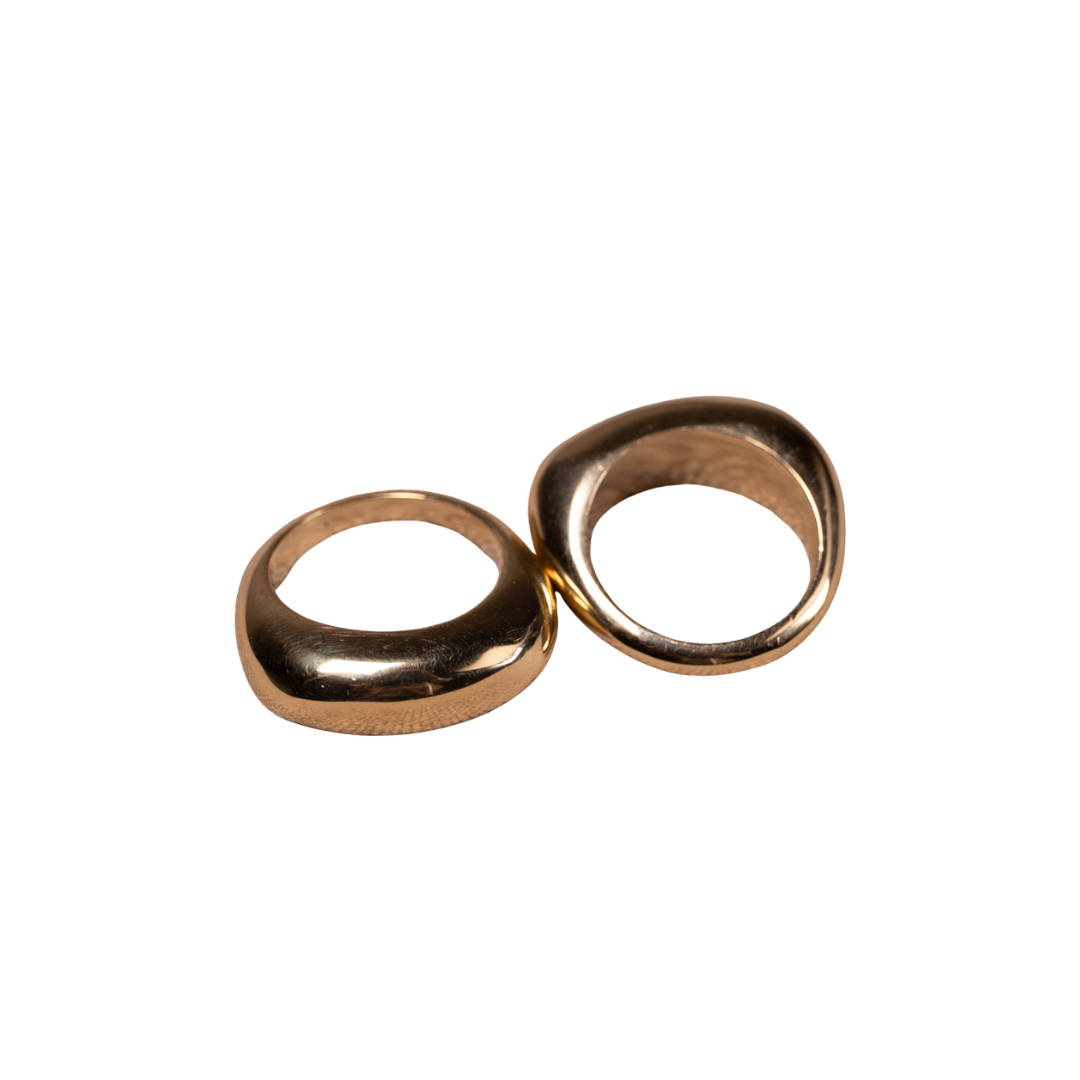 Two smooth, rounded metallic rings in a warm gold finish, positioned side-by-side on a solid white background.