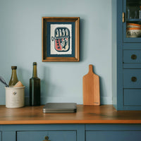 Kitchen counter with a wooden cutting board, bottles, and a framed artwork on a light blue wall.