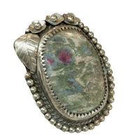 Silver ring with an oval stone featuring floral patterns on a white background
