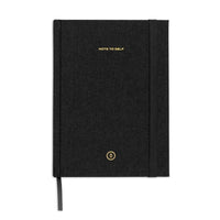 A black textured hardcover notebook with gold foil lettering that reads 'NOTE TO SELF' and a small circular gold logo near the bottom, shown on a plain white background.